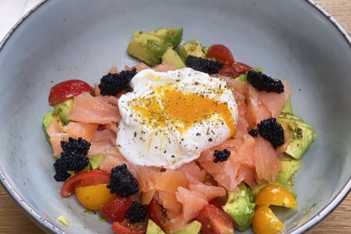 Kom met gerookte zalm, avocado, tomaat, gepocheerd ei en kaviaar