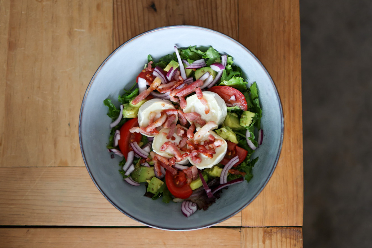 Kom met sla, avocado, tomaat, rode ui, geitenkaas en spekjes